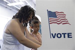 Photo of parent and child in a voting booth together