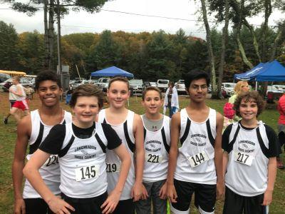6 cross country youth runners standing together smiling in a field